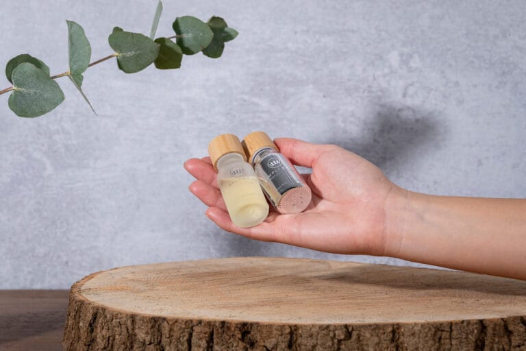 Hand model holding two bottles of essential oils, showcasing the elegant packaging and highlighting the calming, natural essence of the oils.