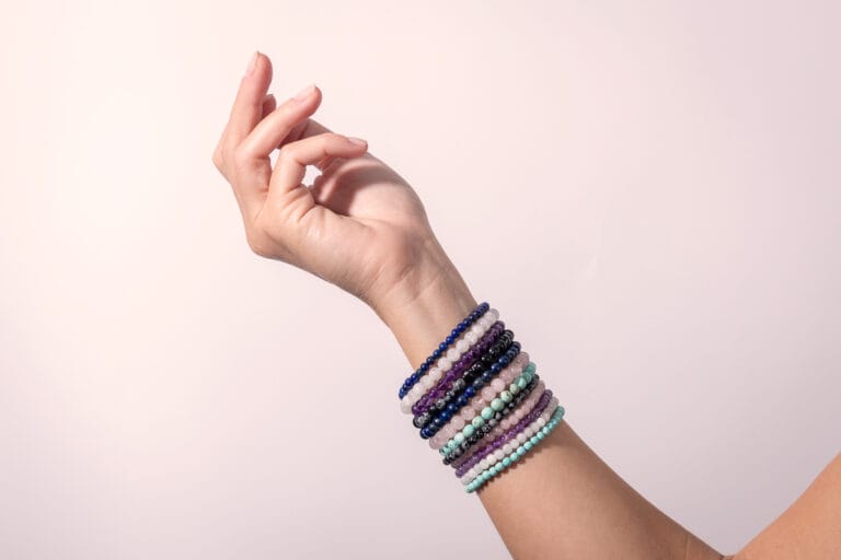 Arm adorned with multiple colorful bracelets, displayed on a simple white background, showcasing the vibrant mix of designs and bold, eclectic style.