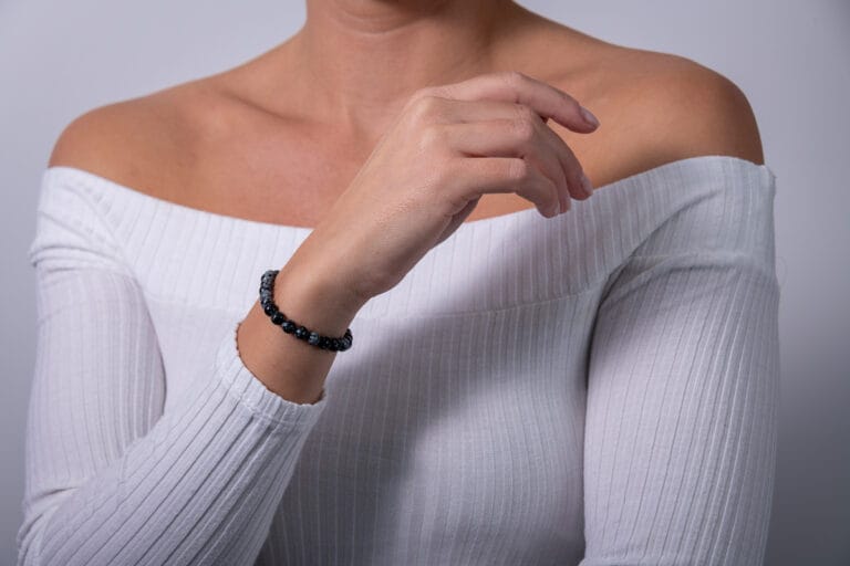 Hand model wearing a white jumper, showcasing a black and grey beaded bracelet, highlighting the delicate design and elegant style of the jewelry.