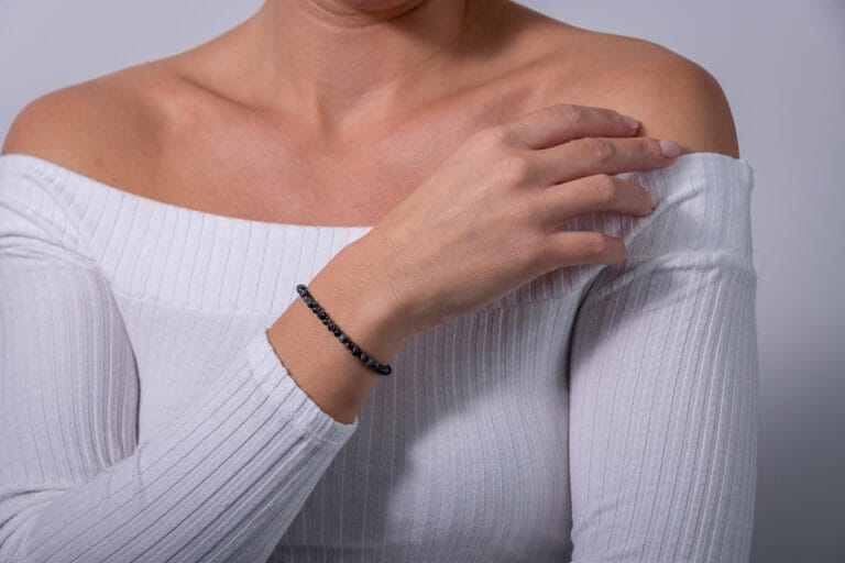Hand model wearing a white jumper, showcasing a black beaded bracelet, highlighting the delicate design and elegant style of the jewelry.