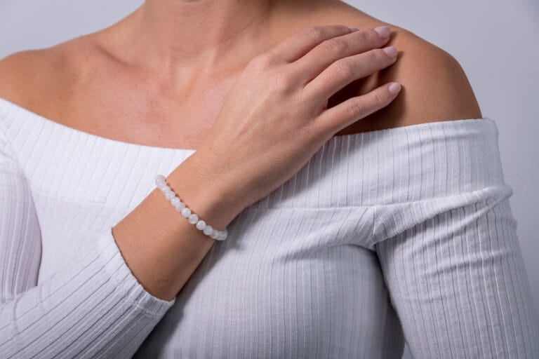 Hand model wearing a white jumper, showcasing a white beaded bracelet, highlighting the delicate design and elegant style of the jewelry.