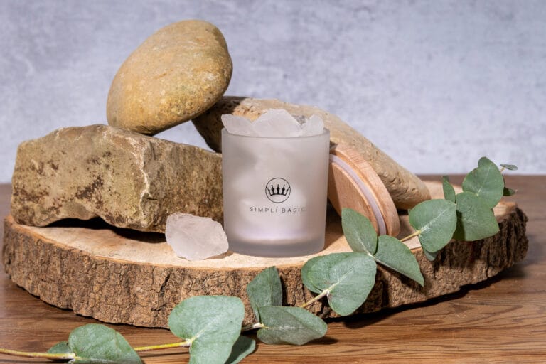 Glass stone diffuser with a wooden lid, surrounded by rocks and foliage, placed on a round of wood, creating a calming, natural setting that highlights the elegance of the diffuser.