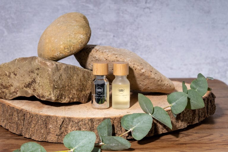 Essential oils placed on a round of wood, surrounded by rocks, creating a calming and natural setting that highlights the soothing properties of the oils.