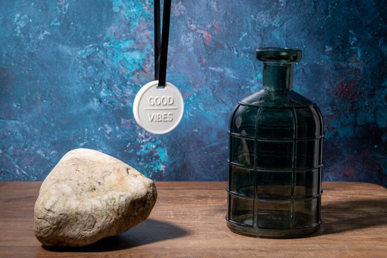 Pendant with "Good Vibes" inscription hanging, set against a background featuring a vase and wooden table, creating a warm and stylish ambiance.