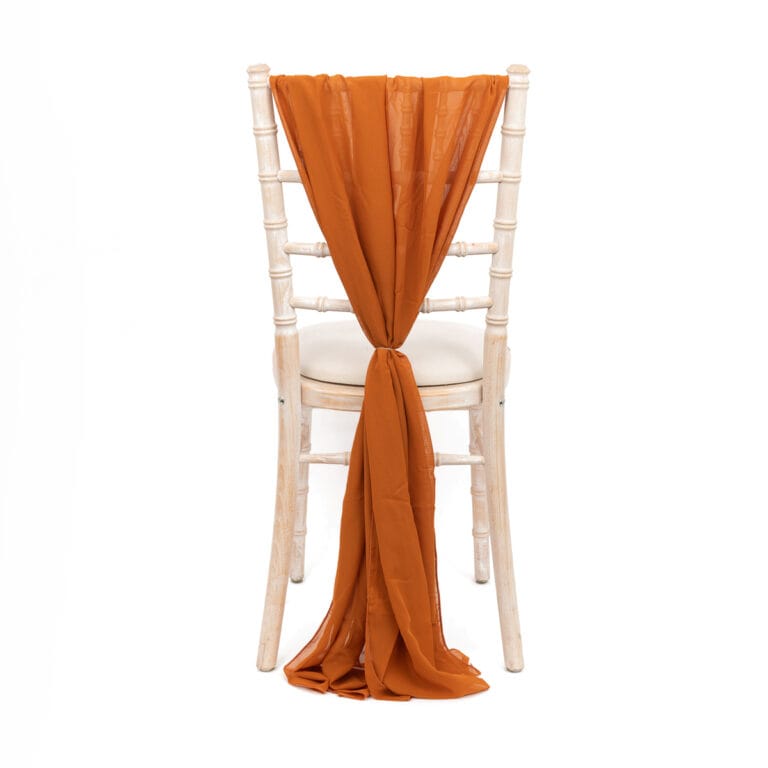 White-washed wooden chair with burnt orange fabric, expertly photographed to highlight its elegant design and vibrant wedding decor potential.